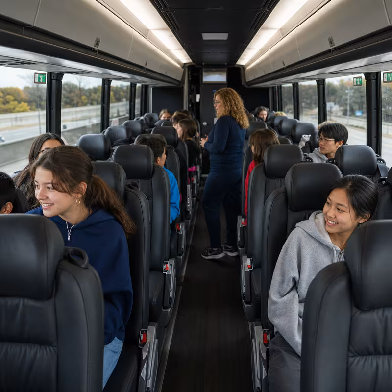 Group boarding a white charter bus for School Transportation transportation in Lincoln