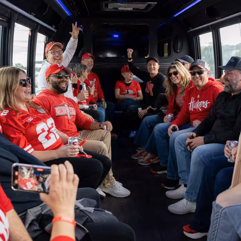 Group boarding a white charter bus for Sporting Event Transportation transportation in Lincoln